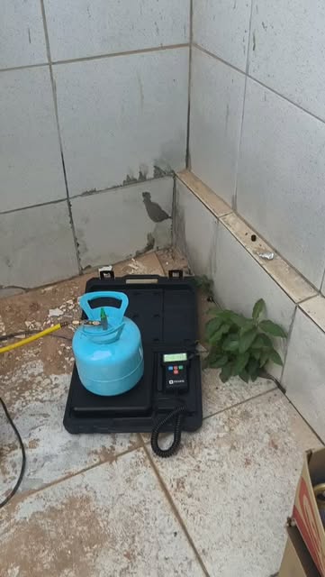 Cilindro de gás refrigerante sobre balança digital durante a carga de gás de um ar-condicionado