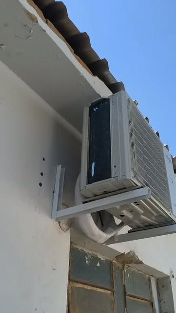 Condensadora de ar-condicionado fixada em suporte sob o beiral do telhado