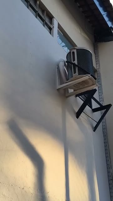Condensadora de ar-condicionado instalada em suporte metálico na parede externa