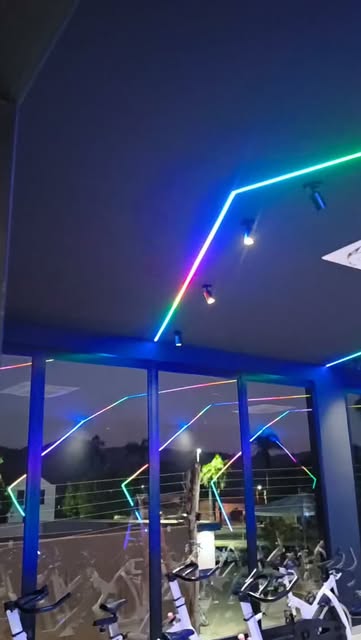 Iluminação em fita LED colorida instalada no teto de uma academia