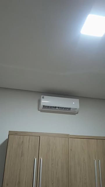 Ar-condicionado split instalado pela FG na parede de um quarto, acima do guarda-roupa